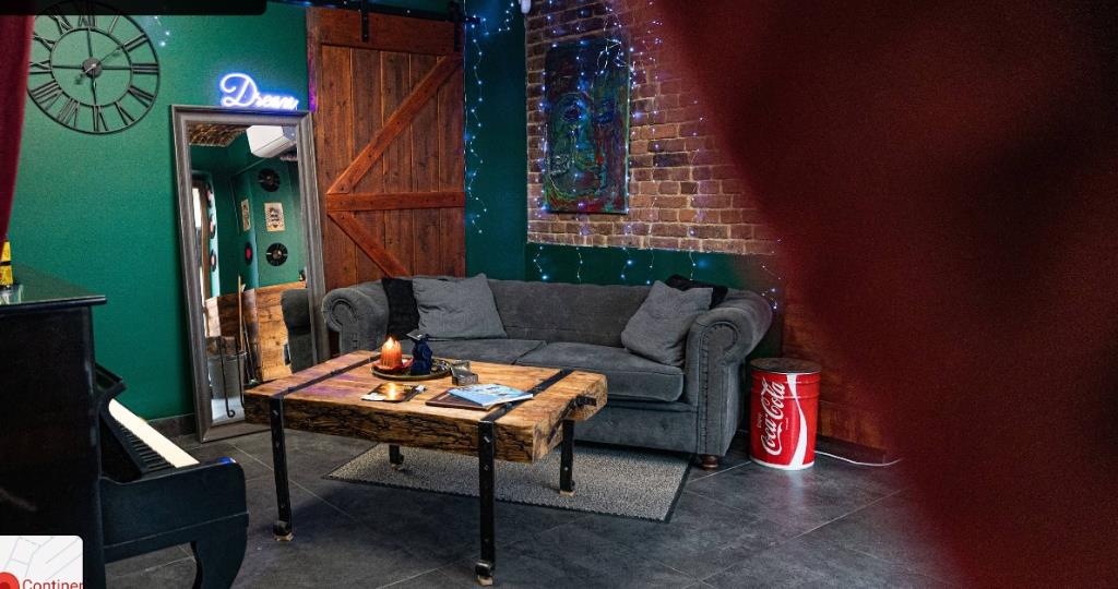 Strefa relaksu lounge z sofą Chesterfield, pianinem i ceglaną ścianą w Continental Barber